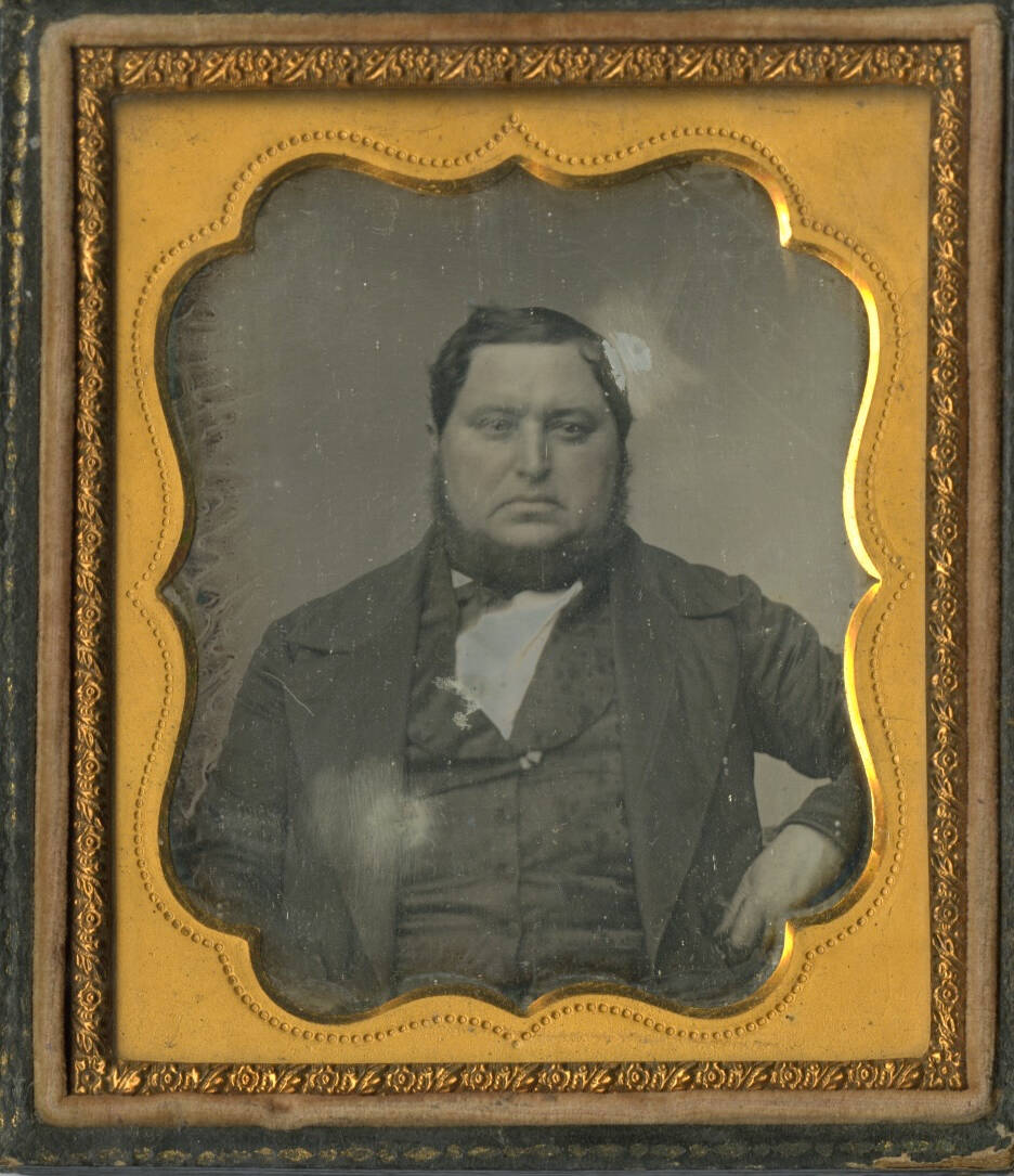Black and white historic daguerreotype photograph of a man with a short beard and suit.